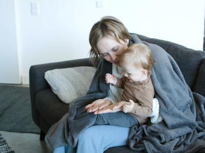 Woman with baby on sofa with blanket